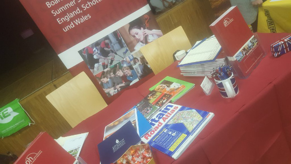 Bücher und Prospekte liegen auf einem Tisch mit roter Tischdecke. Internats-Messe 2019
